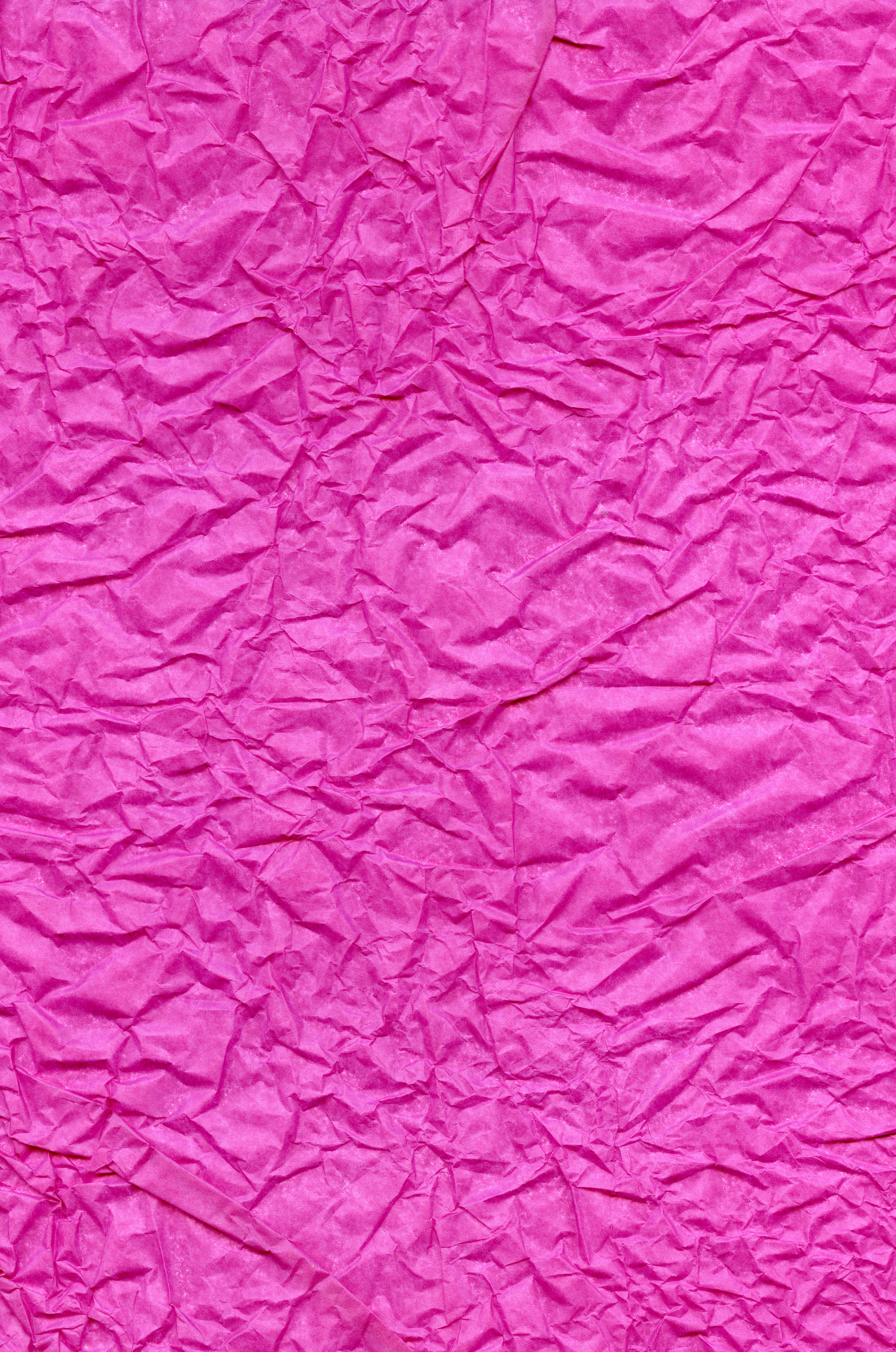 Crumpled pink magenta tissue paper for background or gift wrapping.  Abstract textured wrinkled crimson parchment backdrop.Surface of fuchsia  color wrapping paper with creases texture for background. Stock Photo