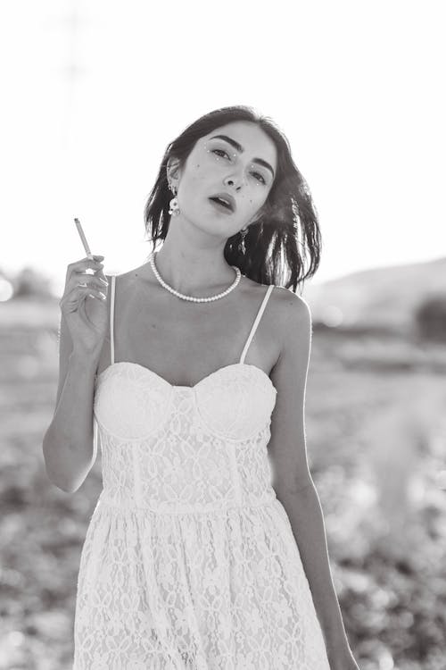 Brunette Woman in White Bustier Dress Holding a Cigarette