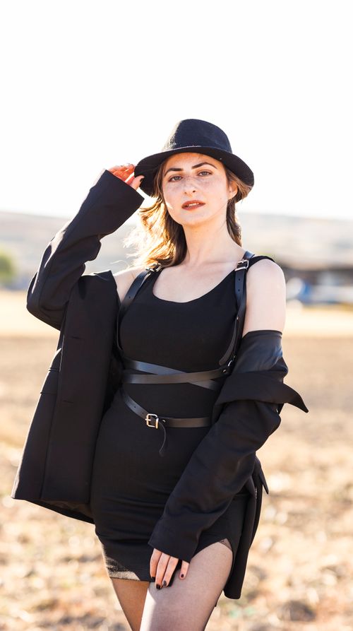 Free Woman wearing black outfit and hat standing in a rural setting, showcasing fashion. Stock Photo