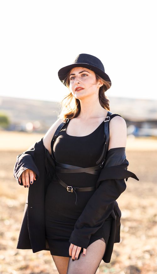Free Fashionable woman in black dress and hat standing outdoors in summer sunlight. Stock Photo