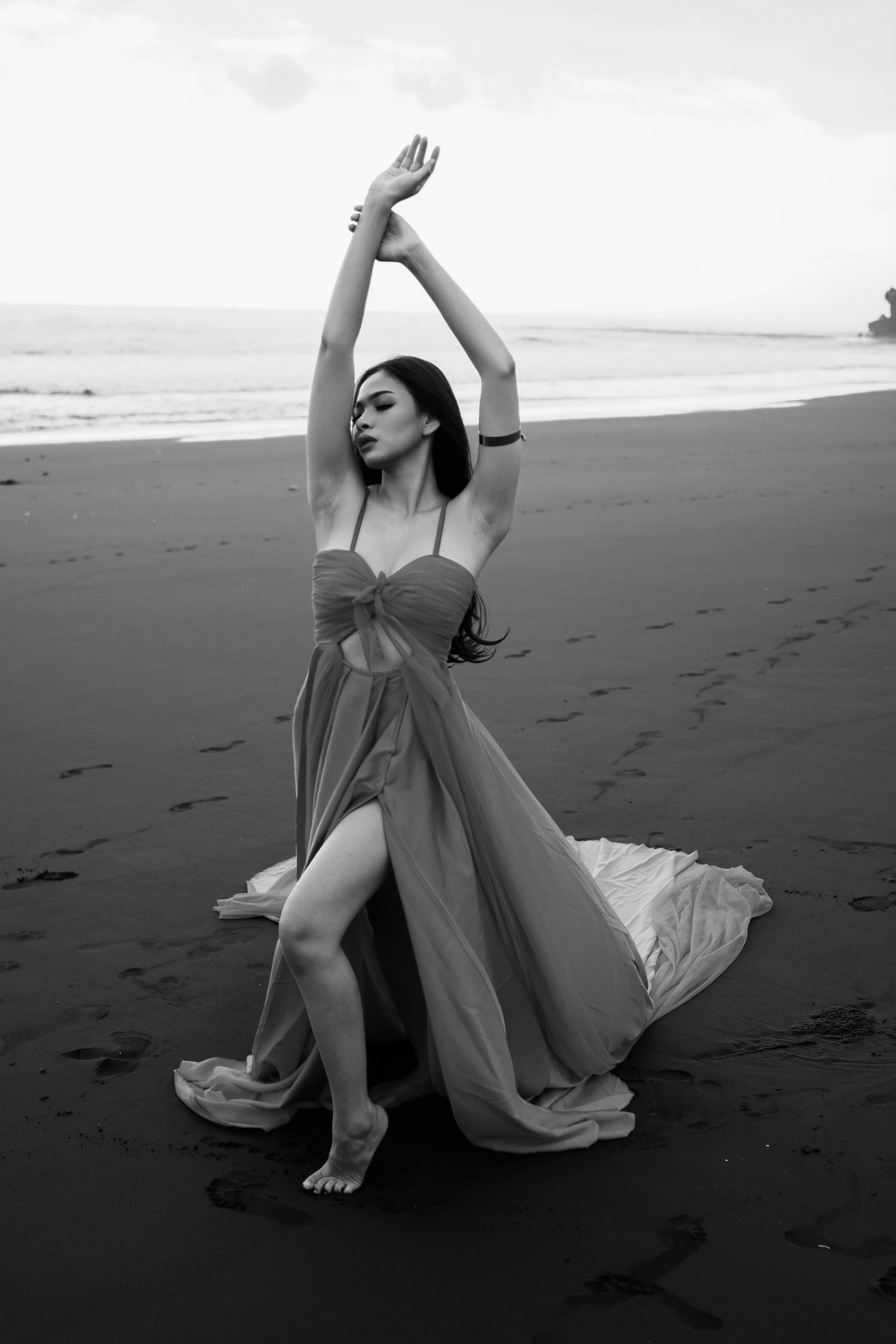 Woman in Dress Posing with Arms Raised on Beach in Black and White ...