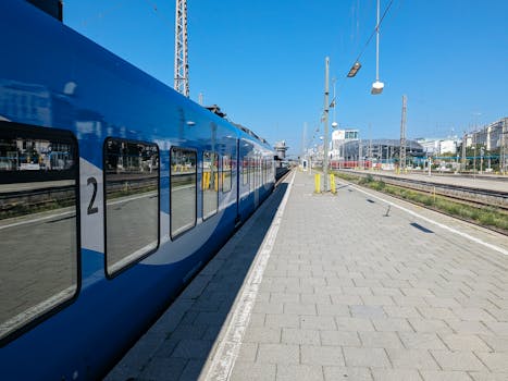 A blue train at an outdoor station platform under a clear sky in Munich.
