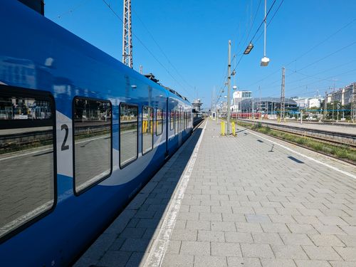 Free A blue train at an outdoor station platform under a clear sky in Munich. Stock Photo