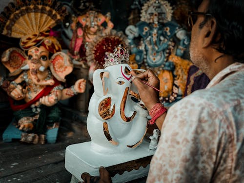 A man is painting a statue of ganesh