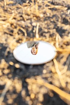 Artistic shot of a woman's reflection in an outdoor mirror, capturing natural beauty.