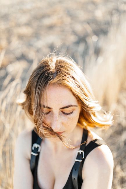 Young woman with light brown hair enjoying the sunlight in a golden field.