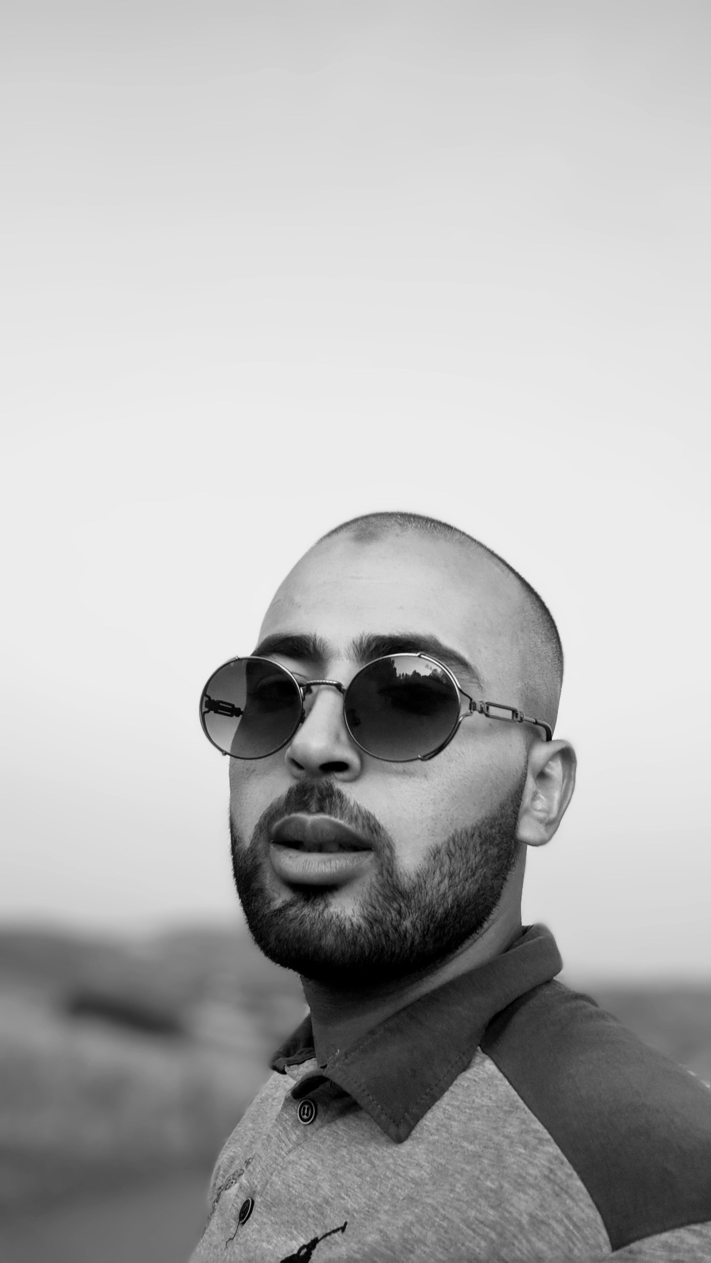 Black and white portrait of a man with sunglasses and a beard, outdoors in El Harrouch.