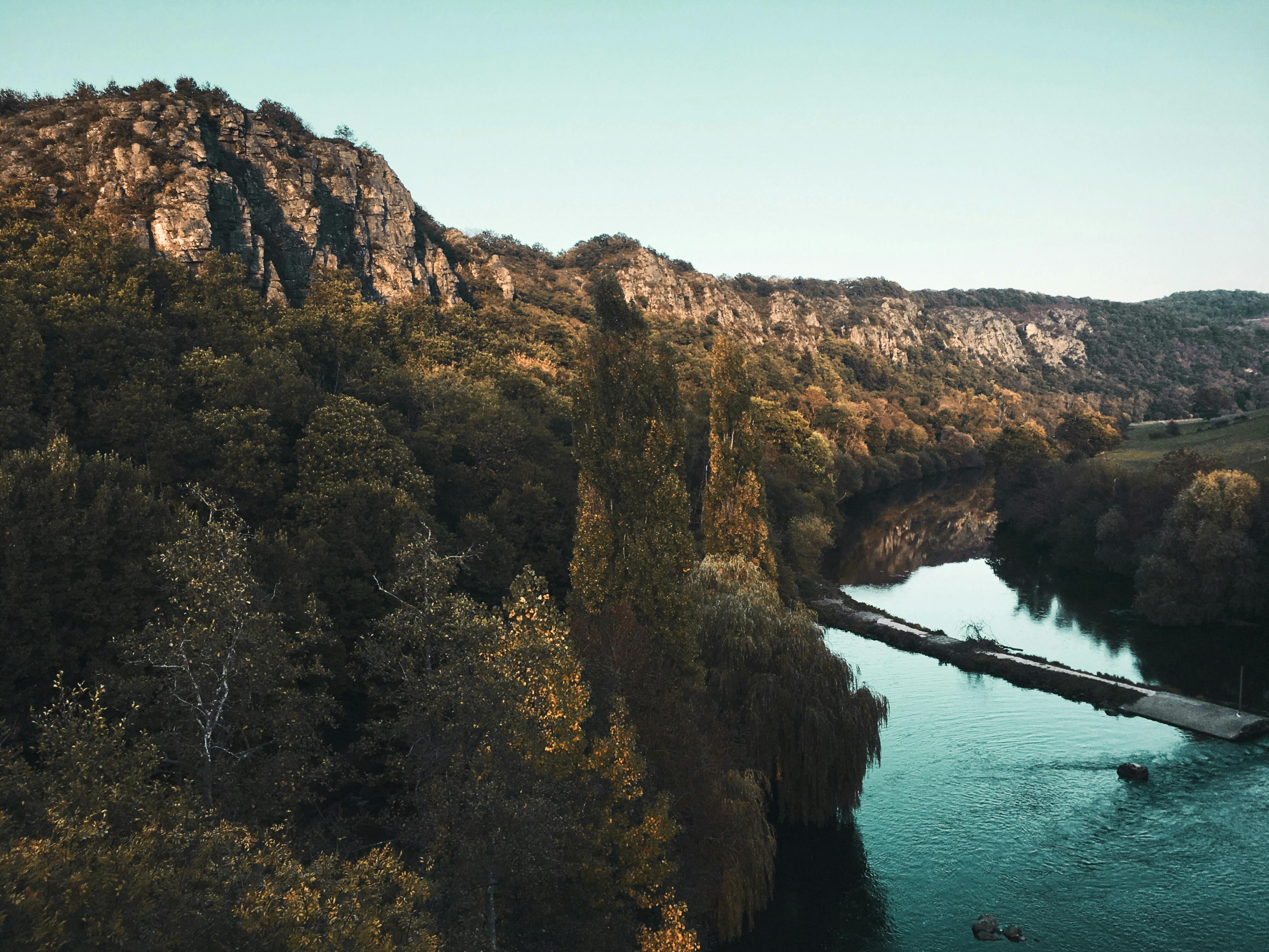 在晴朗的天空下，一条宁静的河流穿过树木茂盛的岩石景观