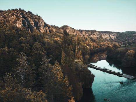 在晴朗的天空下，一条宁静的河流穿过树木茂盛的岩石景观