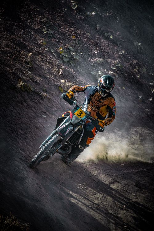 Free Rider in full gear maneuvers sharply during an exhilarating off-road motorcycle race. Stock Photo