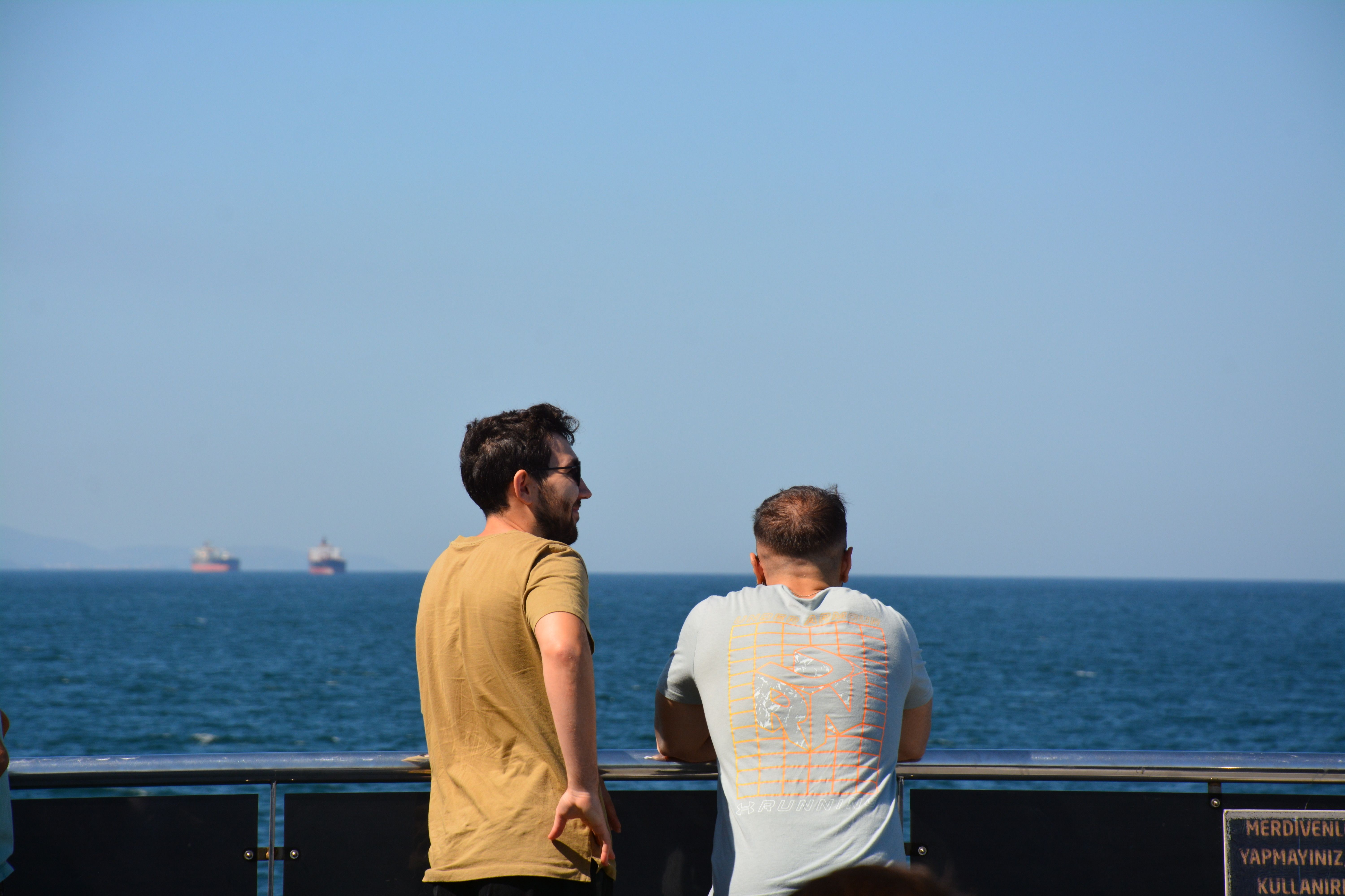 Two Men Standing at a Waterfront and Looking at Sea · Free Stock Photo
