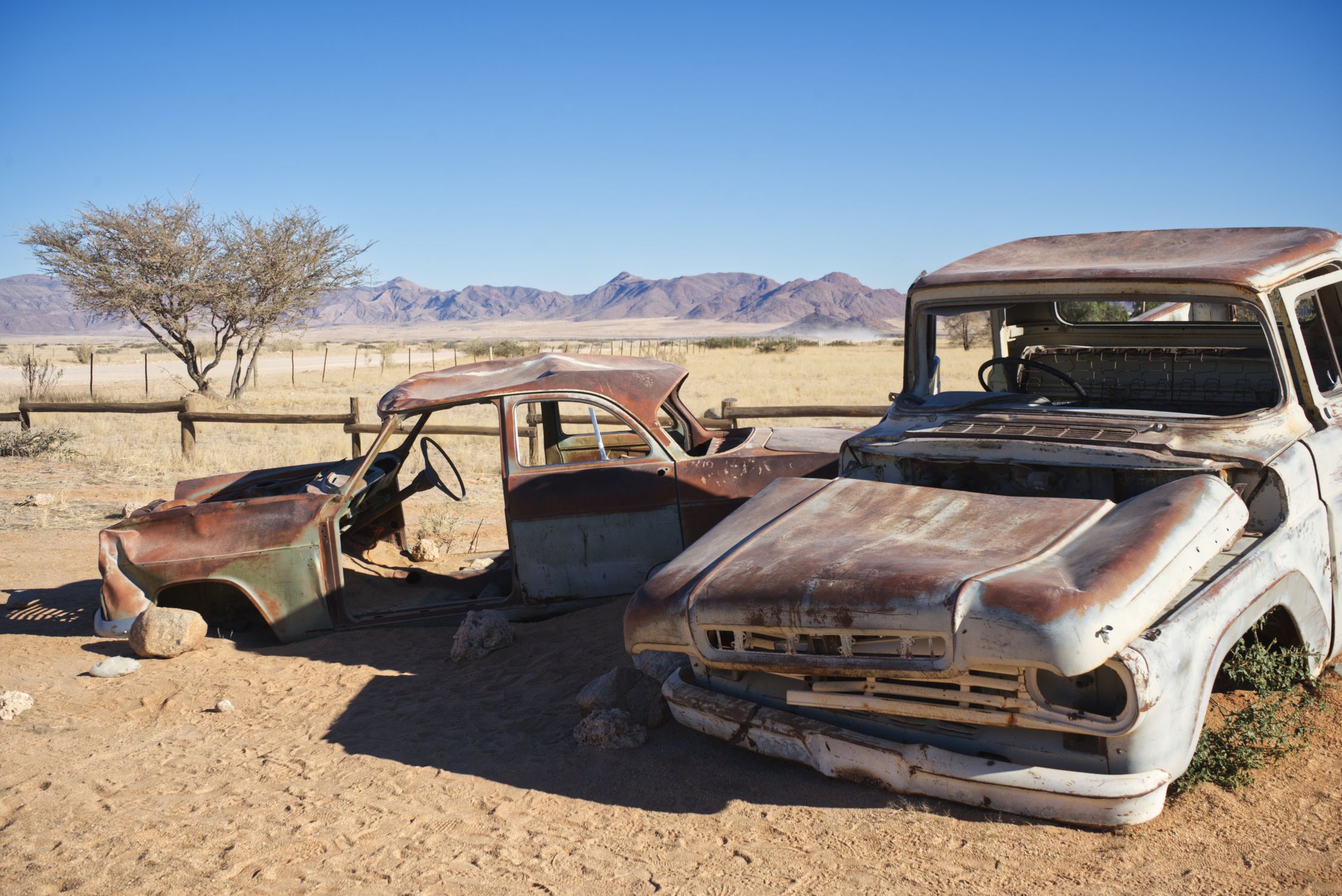 Old rusty vehicles in Solitaire, Namibia's desert with mountains in the backdrop