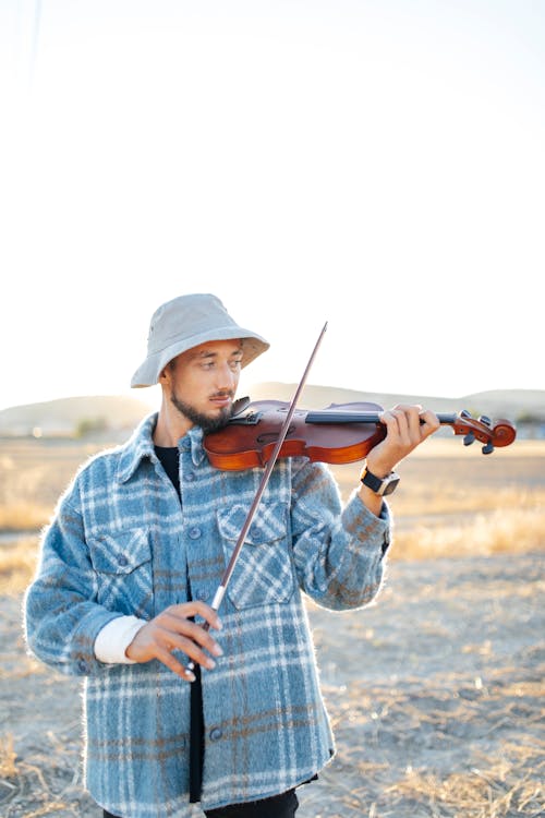 Man in Hat Playing Violin on Field