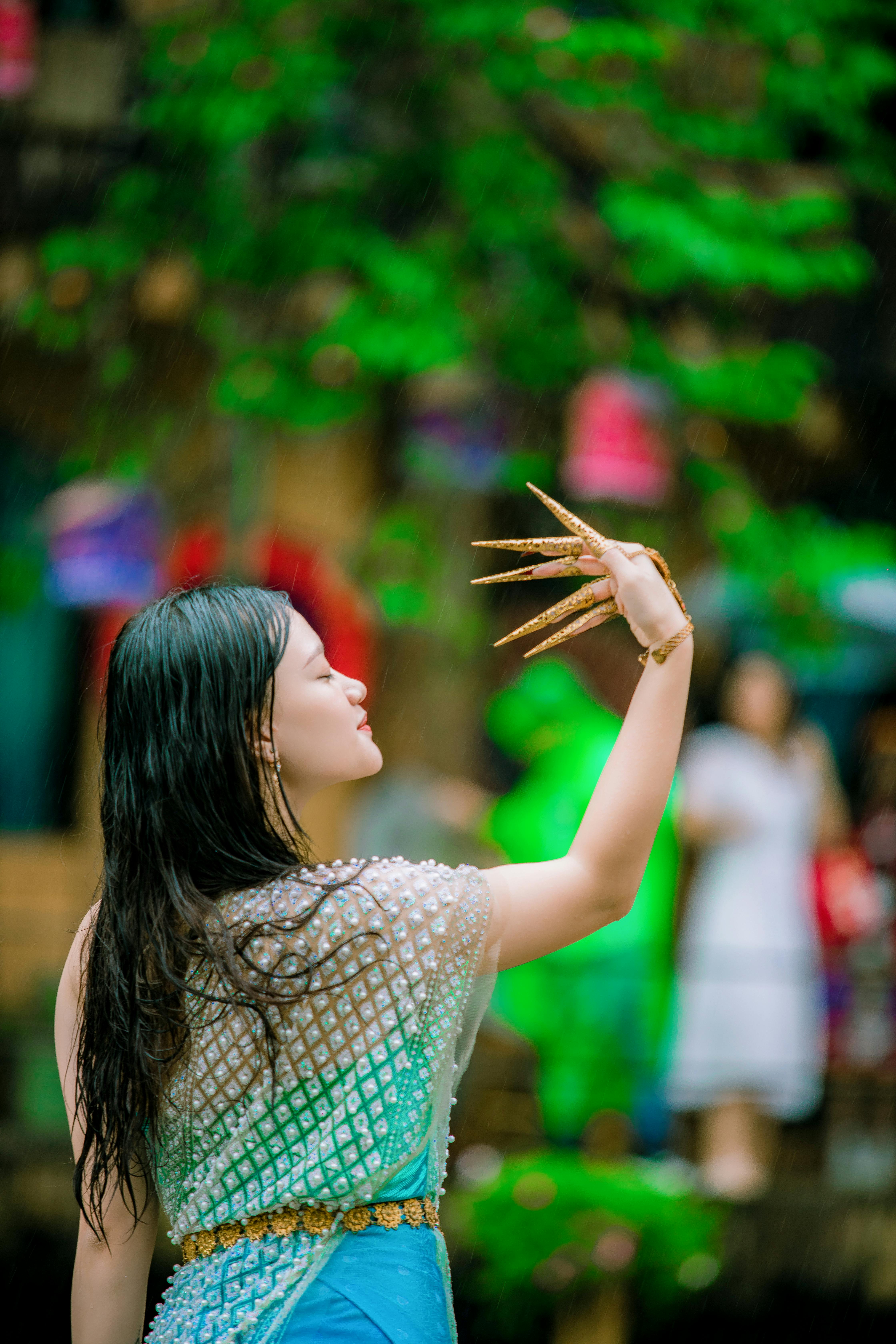 Woman performing traditional dance with grace in an outdoor setting, adorned in cultural attire.