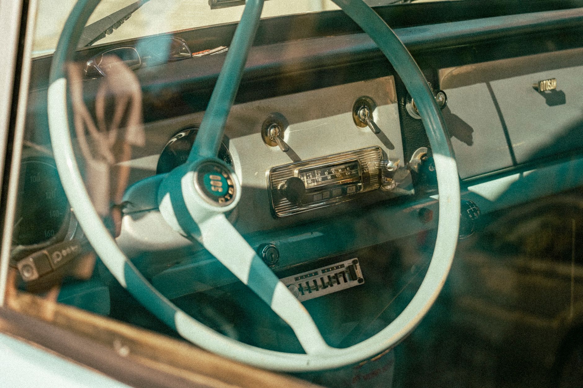 Close-up of a vintage car's interior showcasing a retro steering wheel and dashboard.