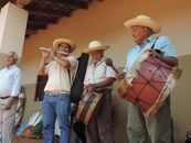 Men in straw hats playing drums and flute in an outdoor setting.