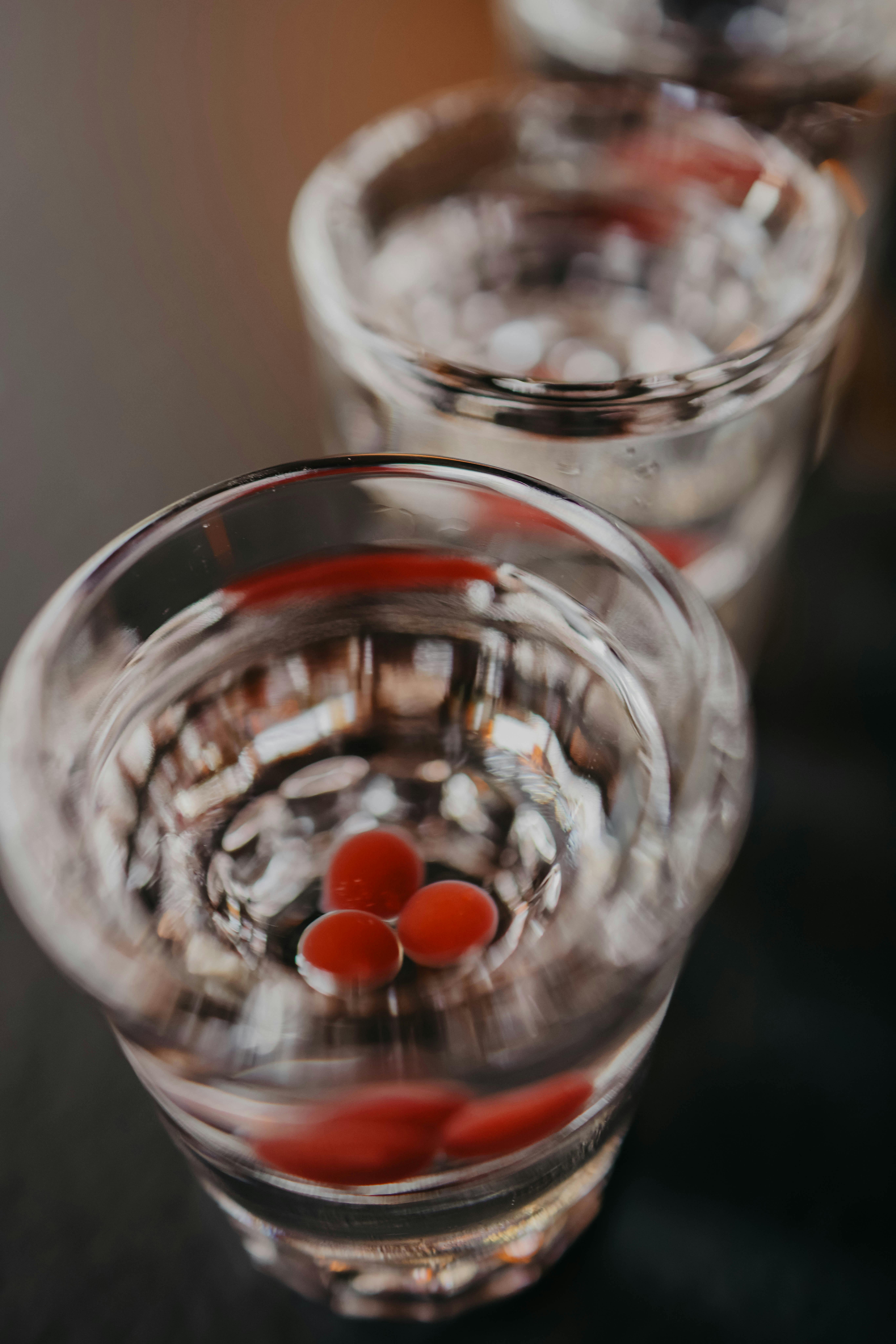 Three vodka shots with cranberries floating inside, arranged in a vertical alignment.