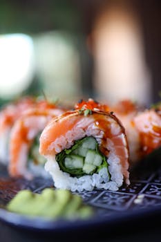Delicious fresh sushi roll with salmon, cucumber, and wasabi on a plate, perfect for food enthusiasts.