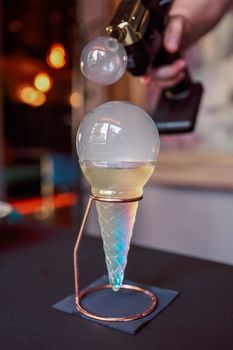 A modern cocktail served with a unique smoky bubble experience on a stylish holder.