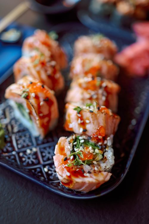 Free Close-up of salmon sushi rolls with sesame seeds and sauce on a decorative plate. Stock Photo