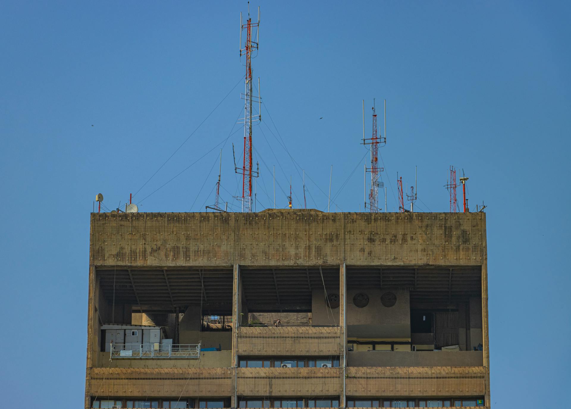 A rooftop in New Delhi features prominent antennas and a clear blue sky.