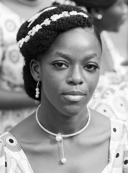 Black and white portrait of a woman wearing a pearl necklace and ornate hairstyle.