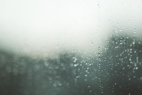 Free Close-up view of a window with raindrops and a soft bokeh background, creating an abstract texture. Stock Photo