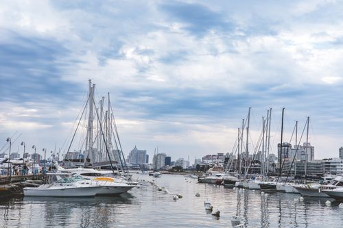 Free A vibrant marina with sailboats and yachts docked under a cloudy blue sky. Stock Photo
