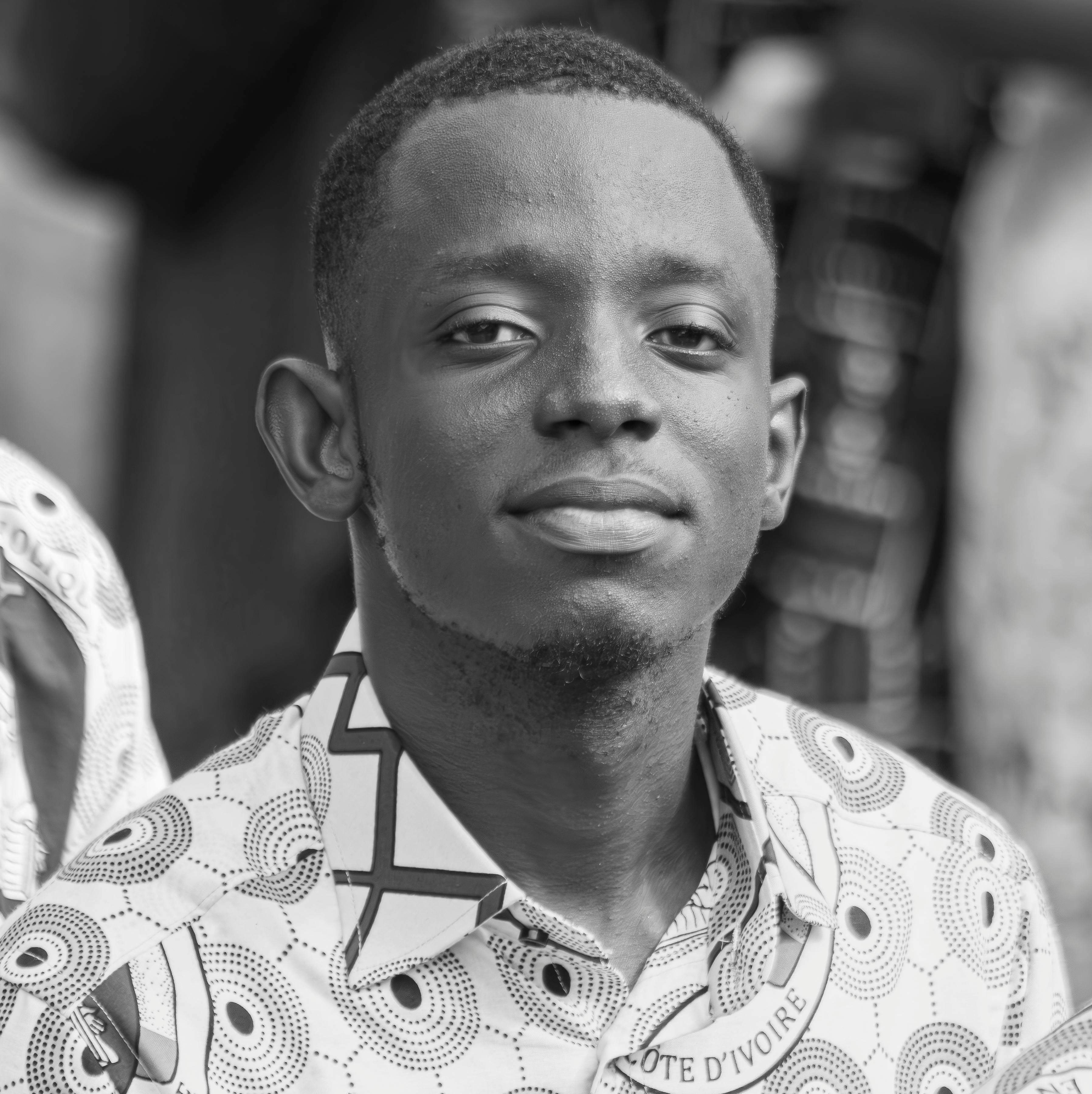 Black and white portrait of a young man in a patterned shirt, looking confident.