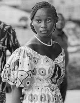 Black and white portrait of an African woman in traditional attire and pearl necklace.