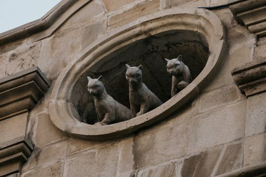 Low angle view of three stone cat statues on a historic building wall in Baku, Azerbaijan.