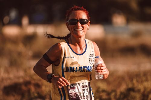 Free A joyful female runner wearing sunglasses during a marathon, holding a water bottle. Stock Photo