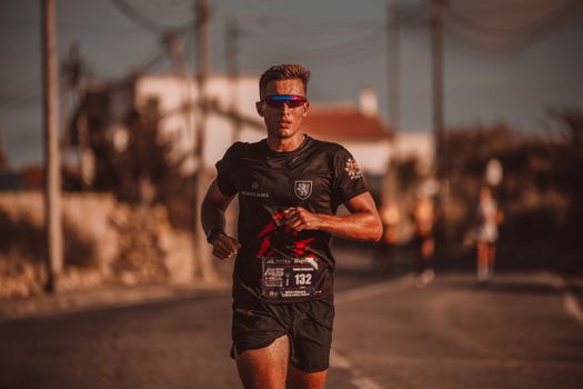 Focused runner wearing sunglasses during an urban marathon, showcasing athletic endurance and determination.