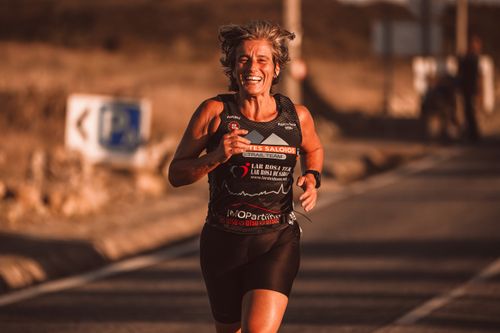 Free Smiling woman running on a sunlit urban street, showcasing fitness and joy. Stock Photo