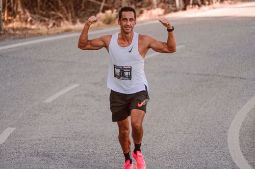 Free A muscular athlete running, flexing arms on an urban road, showing strength and determination. Stock Photo