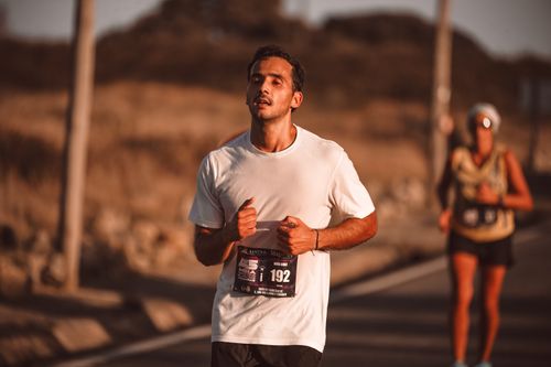 Free A focused runner participating in an outdoor marathon under warm summer sunlight. Stock Photo
