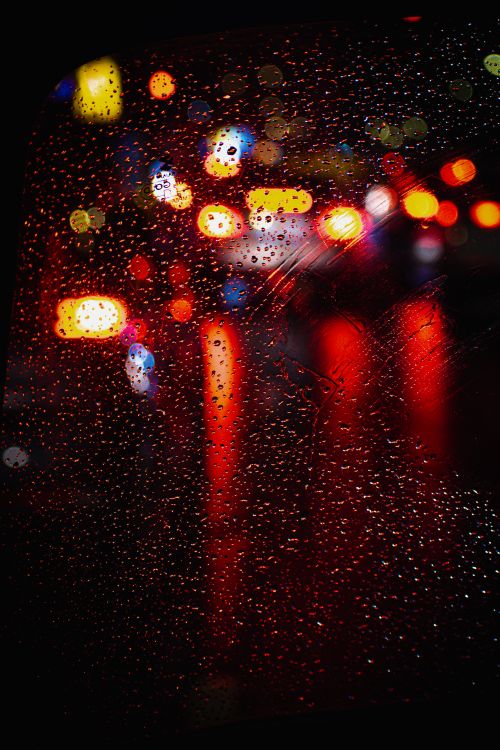 Free Vibrant bokeh of city lights seen through a rain-soaked window at night. Stock Photo