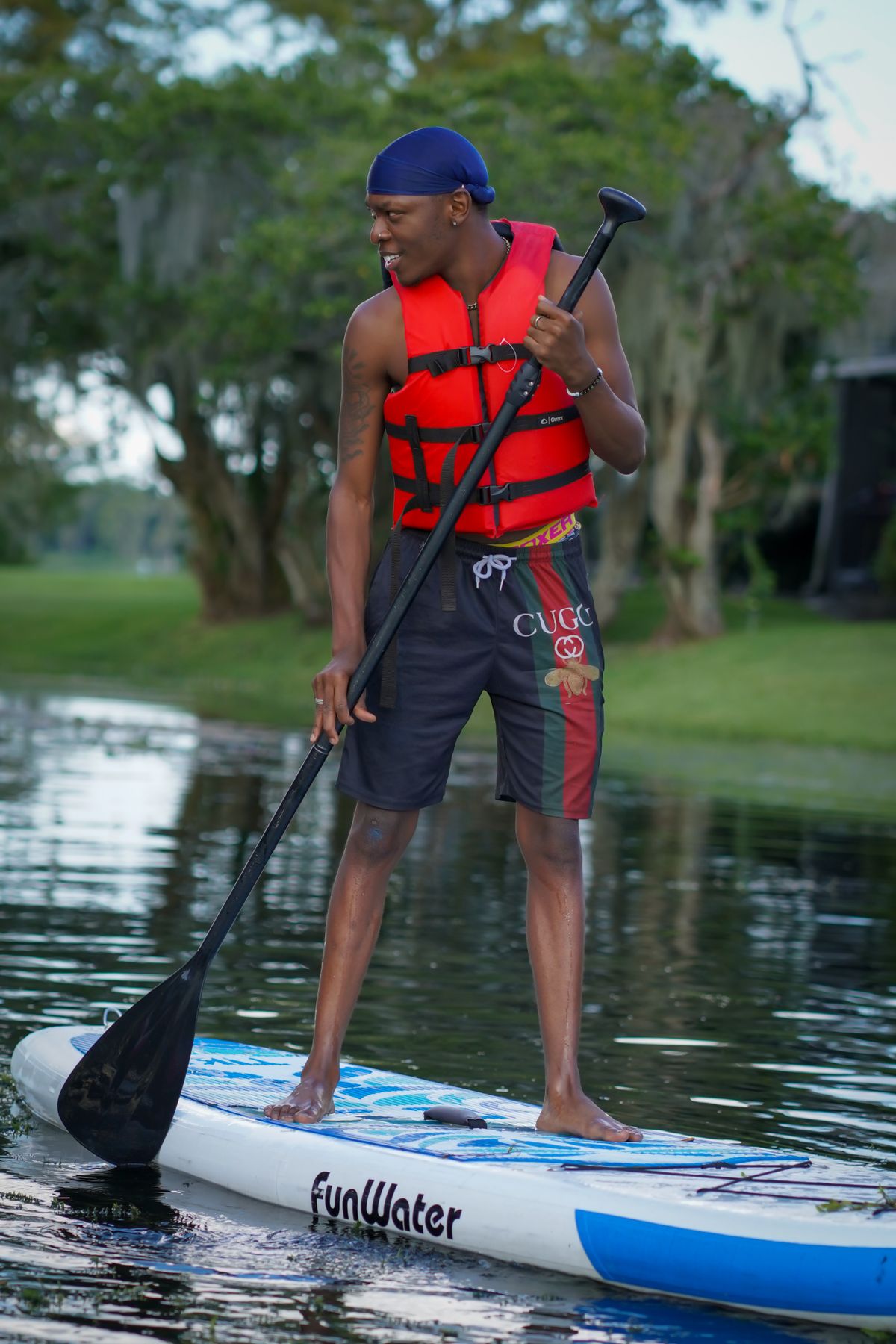 Man in a red life vest paddling on a calm river
