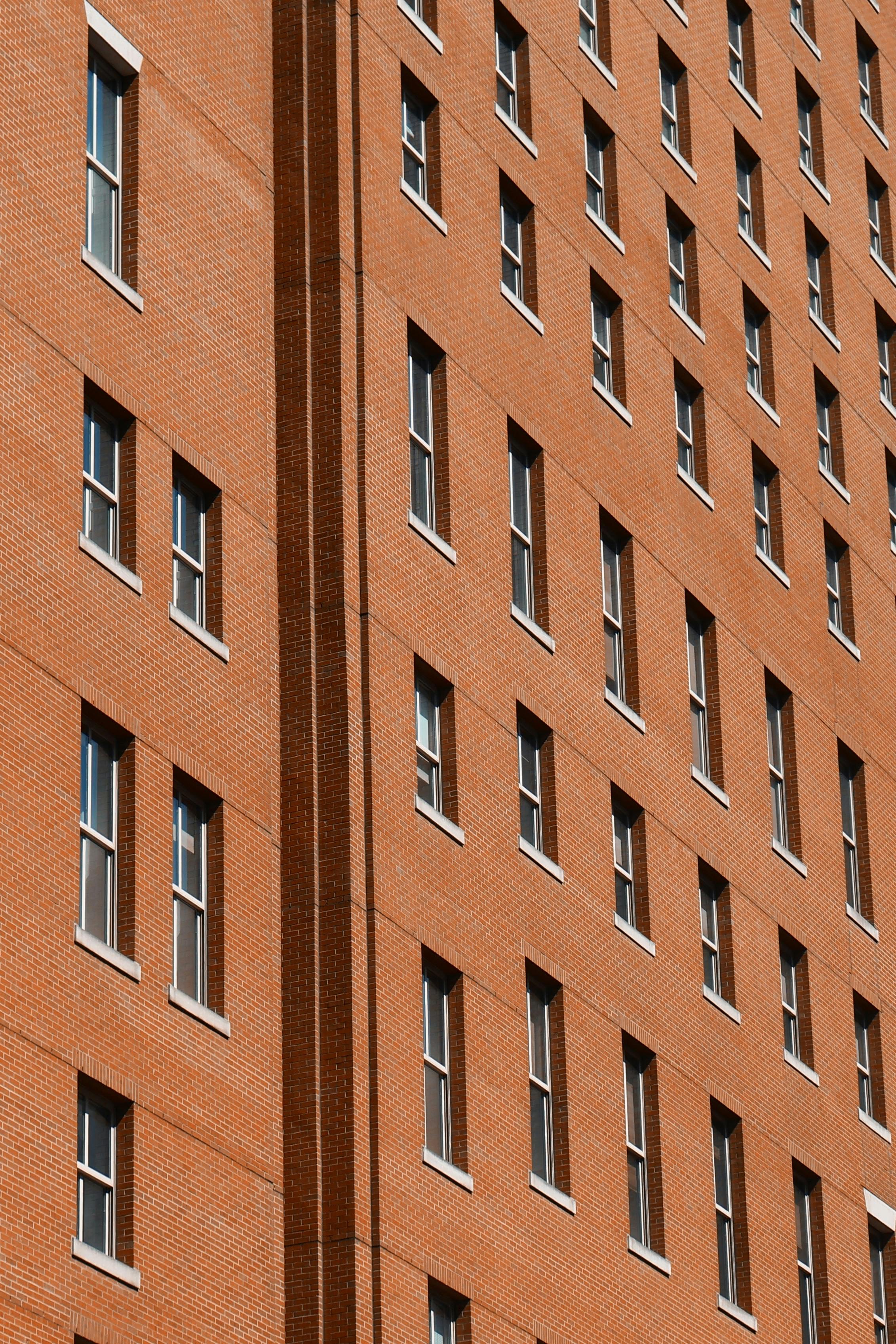 Diagonal view of a red brick building facade with rows of windows in New York City.