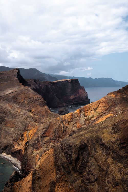 Free A stunning view of rugged cliffs meeting the sea under a dramatic sky. Stock Photo