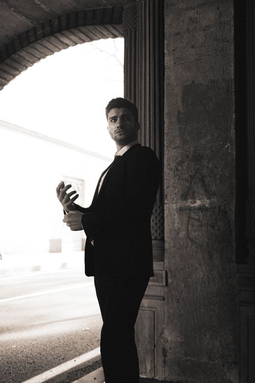 Free A stylish man in a black suit poses under a bridge, evoking classic elegance and urban sophistication. Stock Photo