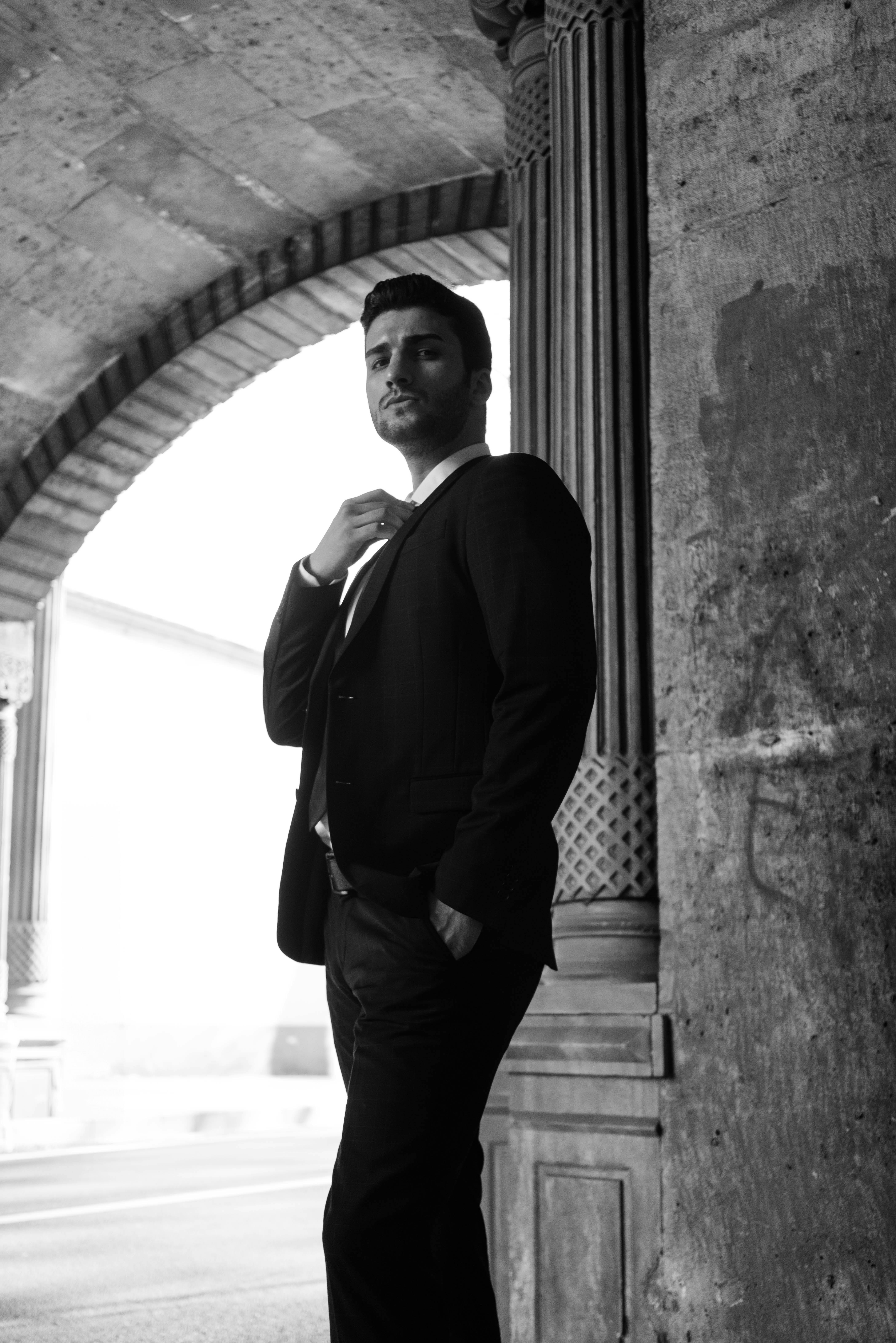 Portrait of a stylish male model in a suit, set in an urban sidewalk, emphasizing classic fashion and elegance.
