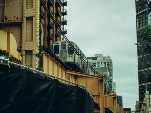 Free A cityscape featuring a train on an overpass amidst modern buildings, capturing urban life. Stock Photo