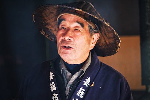Photo of an Elderly Man Wearing an Asian Conical Hat