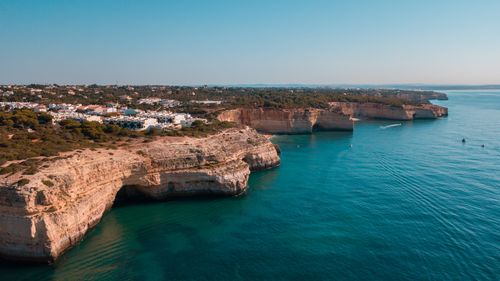 Free Stunning aerial view of Algarve coastline with cliffs and turquoise sea under blue sky. Stock Photo