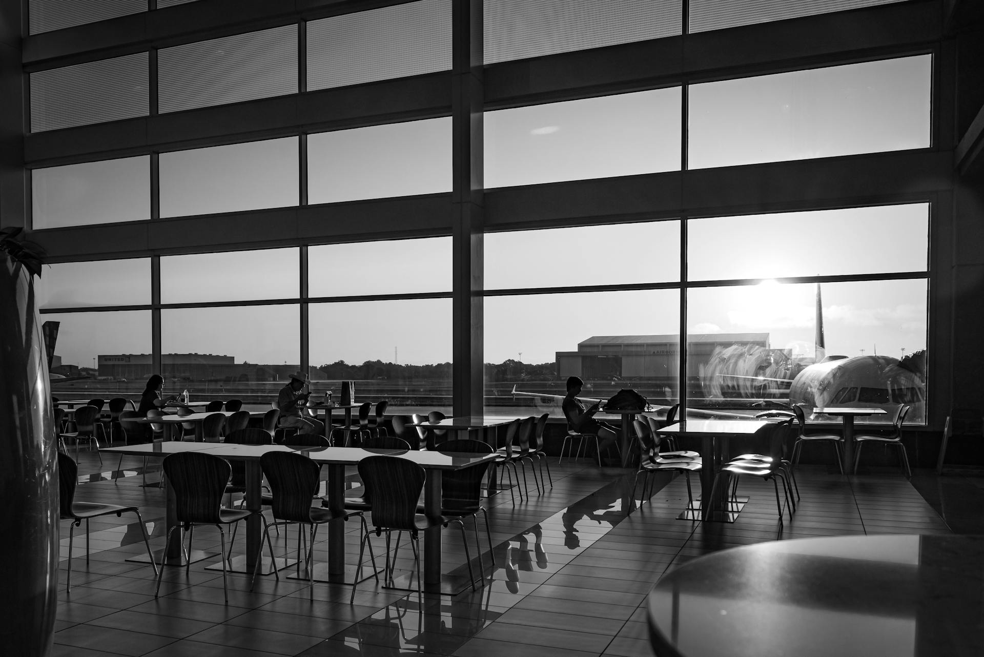 A serene view of an airport terminal interior with sunlight streaming through large windows.