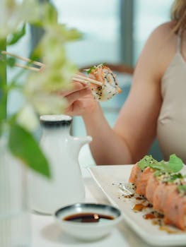 Close-up of a woman holding sushi with chopsticks. Modern dining experience.