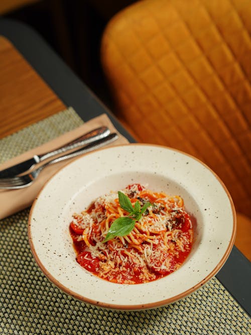 Spaghetti with Tomato Sauce Sprinkled with Parmesan and Topped with a Basil Leaves