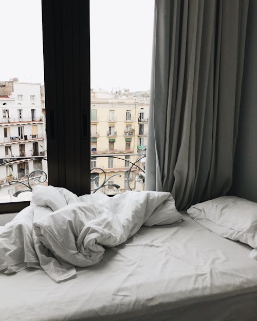 White Bedspread Beside Glass Sliding Door