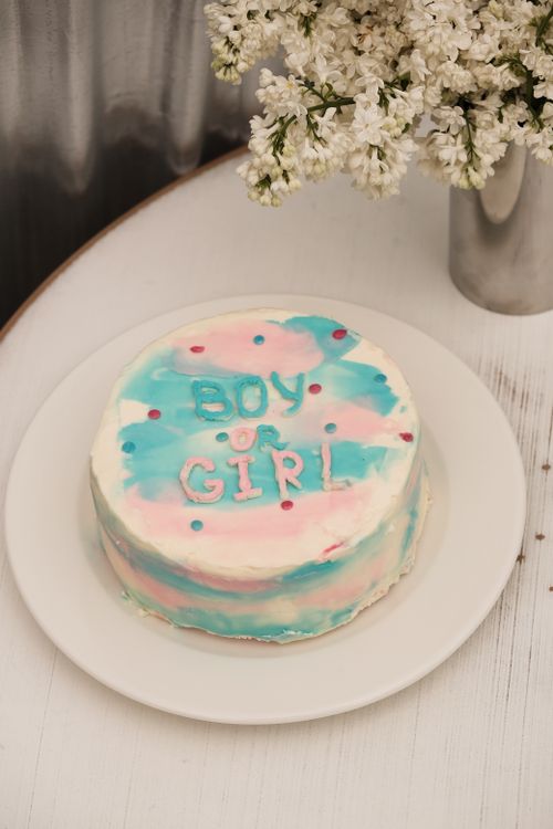 Free Colorful gender reveal cake with flowers on a table, perfect for celebrations. Stock Photo